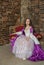 Young beautiful woman in fantasy white and purple rococo style medieval dress sitting in the armchair