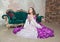 Young beautiful woman in fantasy white and purple rococo style medieval dress sitting on the floor and praying