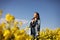 Young beautiful woman in a field with yellow blooming rapeseed. girl in yellow floral field, rapeseed plantation, summer vacation