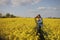 Young beautiful woman in a field with yellow blooming rapeseed. girl in yellow floral field, rapeseed plantation, summer vacation