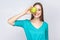 Young beautiful woman with freckles and green dress holding apple in front of her eyes and smiling . studio shot