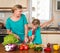 Young beautiful woman and girl making fresh vegetable salad. Healthy domestic food concept. Smiling mother and funny playful daugh
