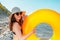 Young beautiful woman in glasses and hat holding an orange swimming circle. The concept of holiday resort and travel