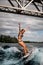 Young beautiful woman gracefully balances on surfboard on wave