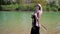 young beautiful woman hangs a handbag on her shoulder while walking along the lake in the park