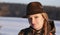 A young beautiful woman with a hat on her head portrait in a snowy landscape. Hunting clothes