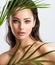 Young beautiful woman with healthy skin of face and palm leaves. Closeup fresh face of an attractive caucasian girl with green