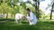 Young beautiful woman with her pet dog Golden Labrador Retriever in the park is having fun blowing dandelion pollen into his snout