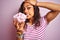 Young beautiful woman holding bowl with marshmallows over isolated pink background stressed with hand on head, shocked with shame