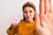 Young beautiful woman holding bowl with marshmallows over isolated white background with open hand doing stop sign with serious