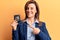 Young beautiful woman holding detective badge smiling happy pointing with hand and finger