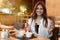 Young beautiful woman holding fork and knife looks hungry ready to eat meat burger with fries for lunch in trendy cafe eating