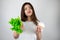 Young beautiful woman holding green salad in one hand and sweet cupcake with cream in another looking frustrated being on diet