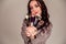 Young beautiful woman holding makeup brushes in her hands and posing on grey background at studio