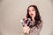 Young beautiful woman holding makeup brushes in her hands and posing on grey background at studio