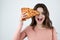 Young beautiful woman holding slice of pizza in one hand near her face looking happy being on diet isolated white background