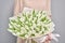 Young beautiful woman holding a spring bouquet of white tulips in her hand. Bunch of fresh cut spring flowers in female