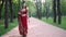 Young beautiful woman in Indian ethnic red saree walking on footpath in the Park