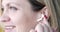 Young beautiful woman inserts wireless headphones into ear closeup