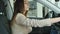 Young beautiful woman inspects the car in showroom