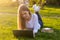 Young beautiful woman with a laptop lies on the grass in spring