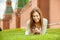 young beautiful woman laughing lies on a green lawn with Mobile Phone