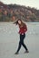 Young beautiful woman with long hair, in black jeans and red shirt, sitting on sand on beach among seagulls birds