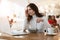 Young beautiful woman looks exhausted while watching at her laptop , eating salad and drinking coffee at lunch time break,