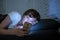 Young beautiful woman lying in bed using smart phone late at night in a dark bedroom.looking worried