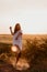 Young beautiful woman making dust with her foot and screaming in the wheat orange field on a sunny summer day. Going