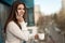 Young beautiful woman manager having phone conversation on the office balcony while drinking her coffee , looking satisfied,