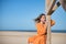 Young and beautiful woman in an orange dress, leaning on a wooden pole, sad, melancholy, depressed, alone. Concept beauty, fashion