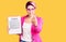 Young beautiful woman with pink hair holding clipboard with contract document beckoning come here gesture with hand inviting