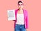 Young beautiful woman with pink hair holding clipboard with contract document puffing cheeks with funny face