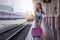 Young beautiful woman with pink luggage walking on platform of railway station