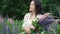 Young beautiful woman posing in a field with a bouquet of lilac flowers. happy brunette in a field of lupins