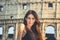 Young beautiful woman posing in front of the Colosseum. Marble arches ruins over a blue sky, Rome, Italy