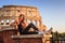 Young beautiful woman posing in front of the Colosseum. Marble arches ruins over a blue sky, Rome, Italy