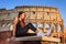 Young beautiful woman posing in front of the Colosseum. Marble arches ruins over a blue sky, Rome, Italy