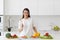 Young beautiful woman preparing a salad of fresh vegetables in a bright kitchen