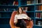 Young beautiful woman in public library, holding, reading and choosing books for leisure or education. Woman making