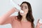 Young beautiful woman putting whipped cream directly to her mouth, looking amazed standing on isolated white background