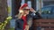 Young beautiful woman in a red beret and dress, black glasses and a braid sitting on a park bench. Photo shoot on the