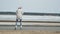 Young beautiful woman in a red hat, wearing sporty warm clothes and rollers, riding on the road on the coast