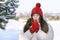 Young beautiful woman in red knitted hat and mittens warms her hands in winter outdoors. Little red riding hood