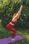 Young beautiful woman in red leggings and a top practicing yoga in a city park