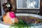 Young beautiful woman relaxing in bath with foam and tropical flowers petals