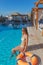 Young beautiful woman is relaxing and swimming in the blue swimming-pool closeup with orange lifesaver.