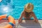 Young beautiful woman is relaxing and swimming in the blue swimming-pool closeup with orange lifesaver.