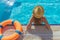 Young beautiful woman is relaxing and swimming in the blue swimming-pool closeup with orange lifesaver.